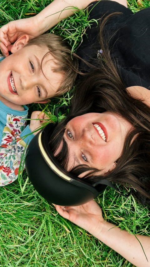 Mother in a Lumos helmet lying on the grass with her son