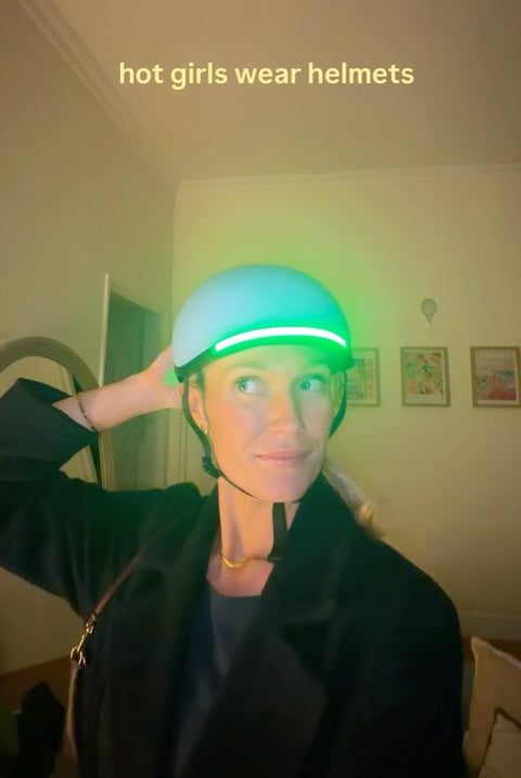 Woman wearing a Lumos helmet with a green light strip
